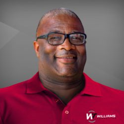 Man in red shirt smiling with glasses.