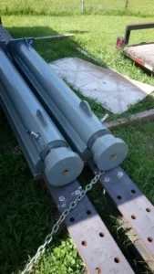 Metal beams on grass beside a trailer.